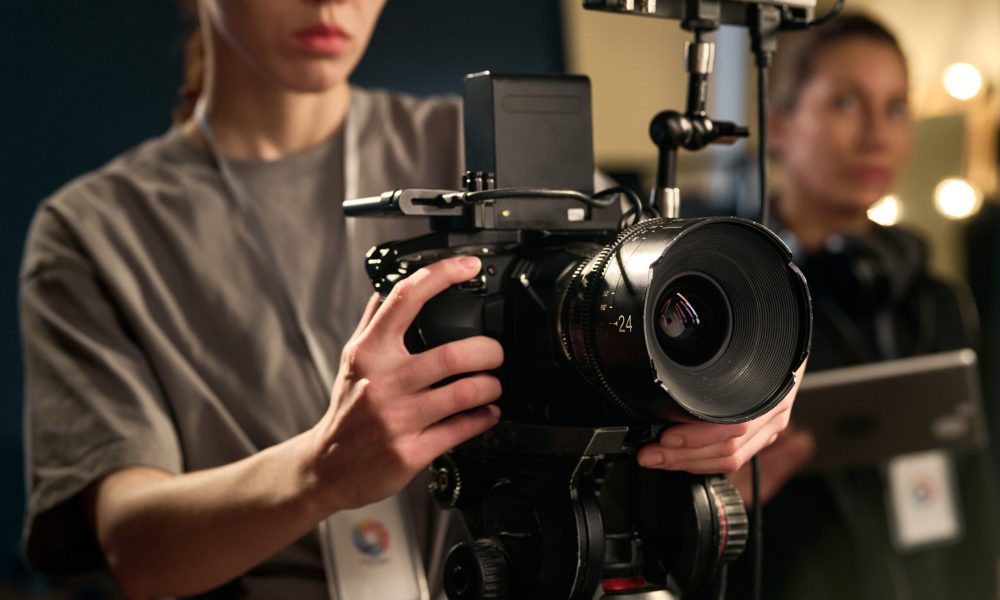 Close up of female hands holding professional video camera and operating equipment on set copy space